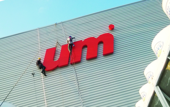 montażyści przy pracy nad literami na elewacji